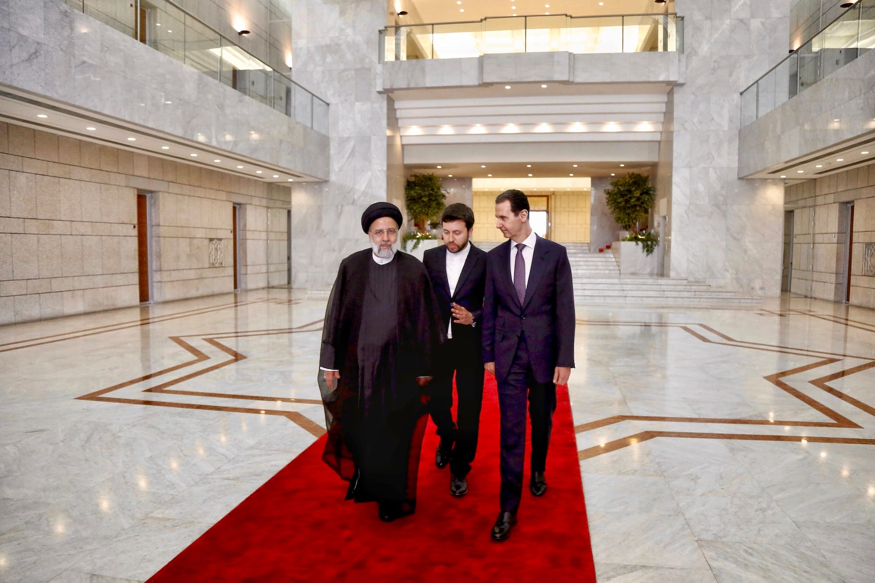 former syria president Bashar al-Assad and Iranian president Ebrahim Raisi walk