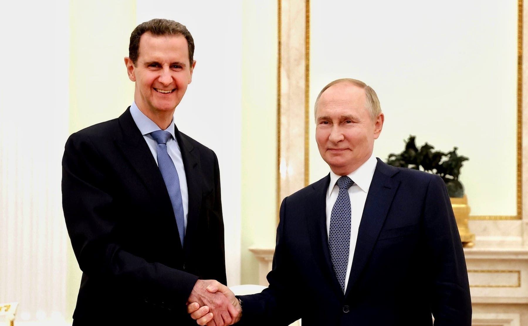 Former Syrian president Bashar al-Assad and Russian president Vladimir Putin shake hands