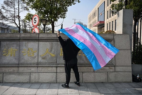 A transgender woman, surnamed Yang, holds a transgender pride flag outside a courthouse in Hangzhou, China, advocating for transgender rights.