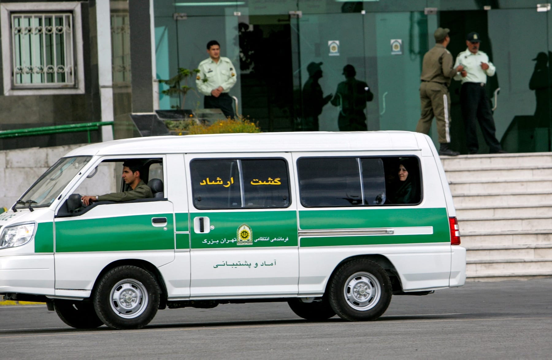 A green-and-white van used by a male Iranian morality policeman departed from the police building and carried a woman in the backseats.