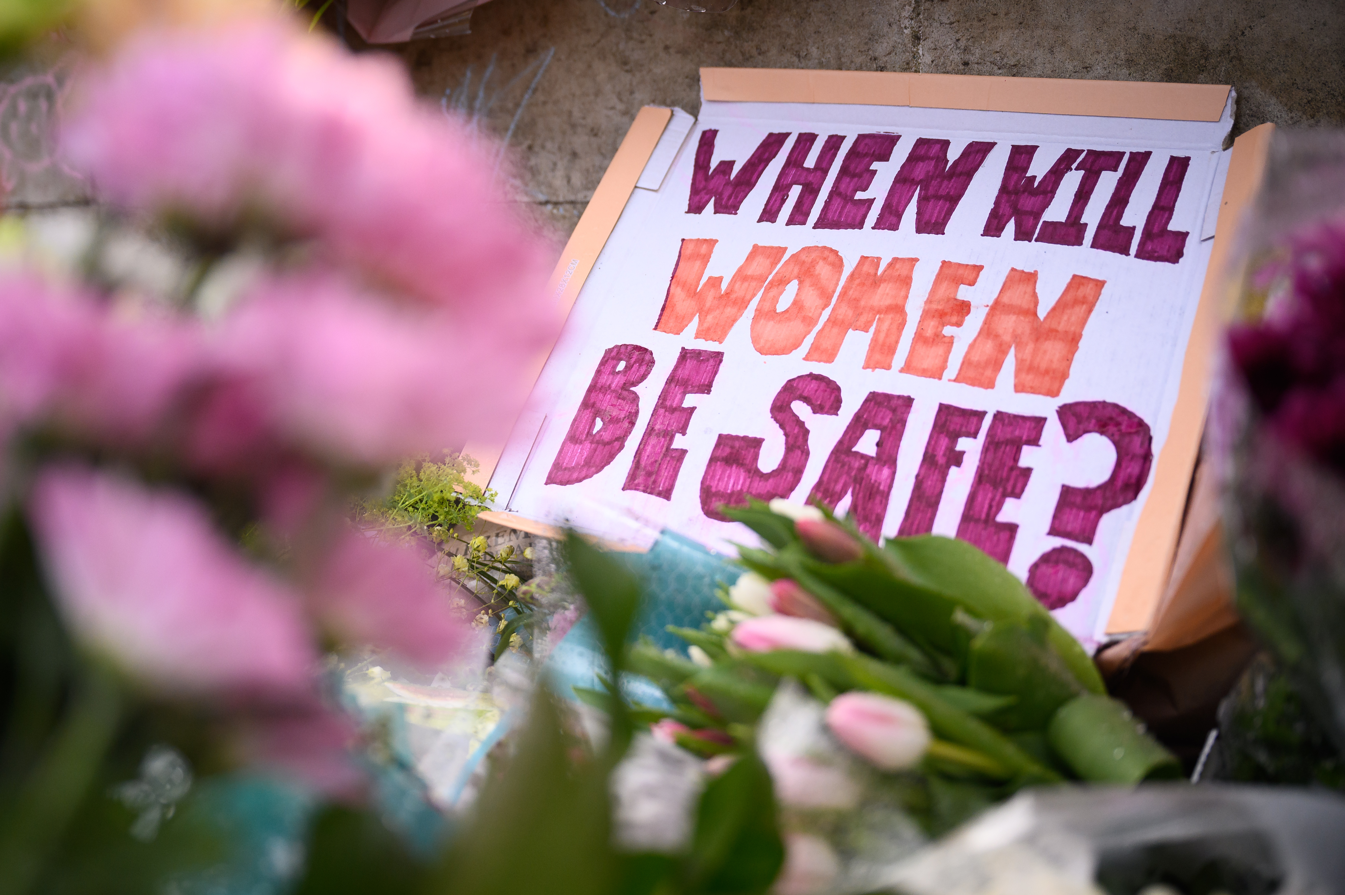 A message "WHEN WILL WOMEN BE SAFE" is seen among flowers on Clapham Common photo.