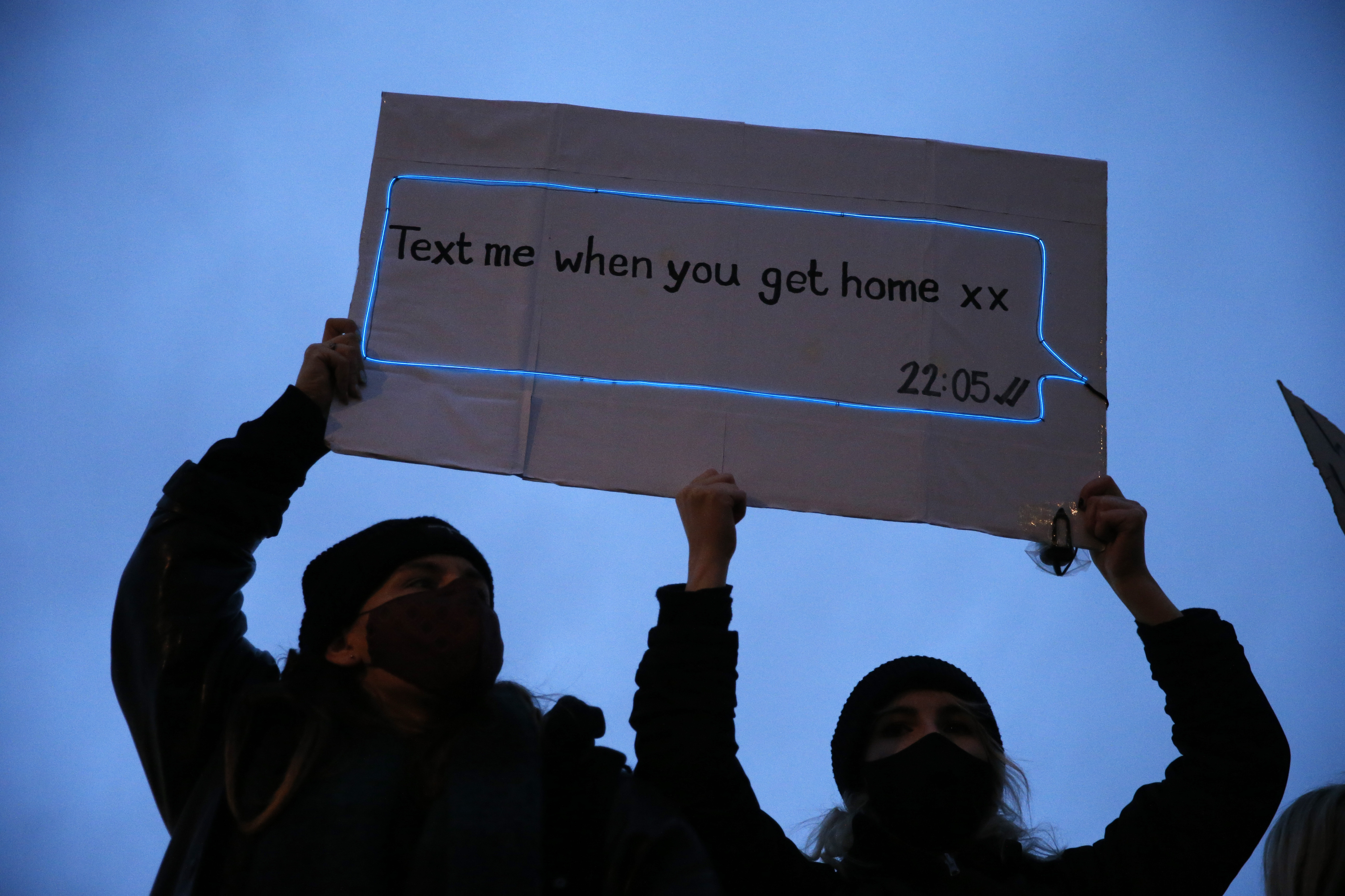 Members of the public hold up a sign reading ''Text me when you get home xx 22:05'' during a protest criticising the actions of the police at last night's vigil photo.