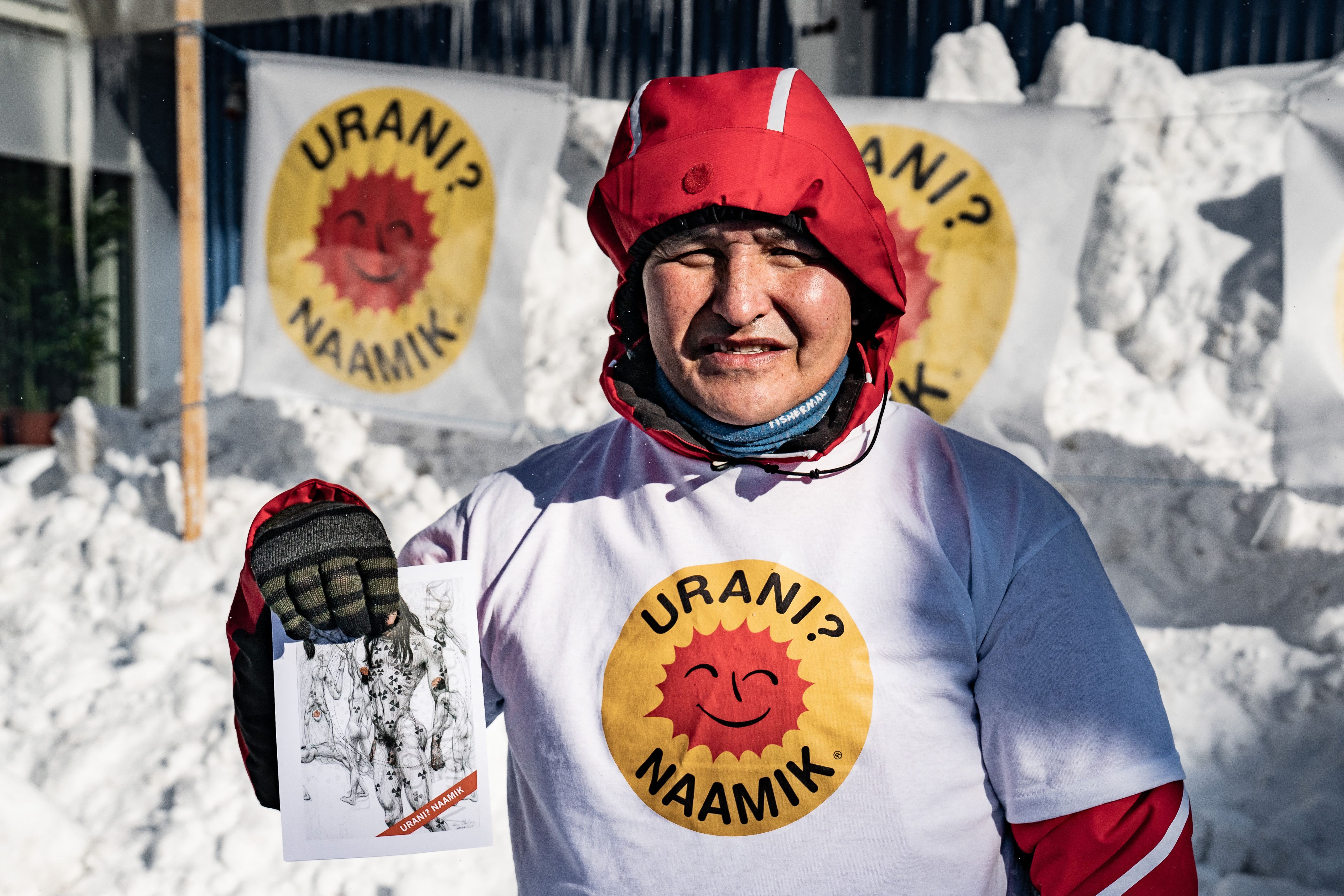 A member of environmental organization Urani Naamik (Uranium, No Thank You) holds up a flyer in front of posters in Nuuk, Greenland, a few days ahead of legislative elections photo.