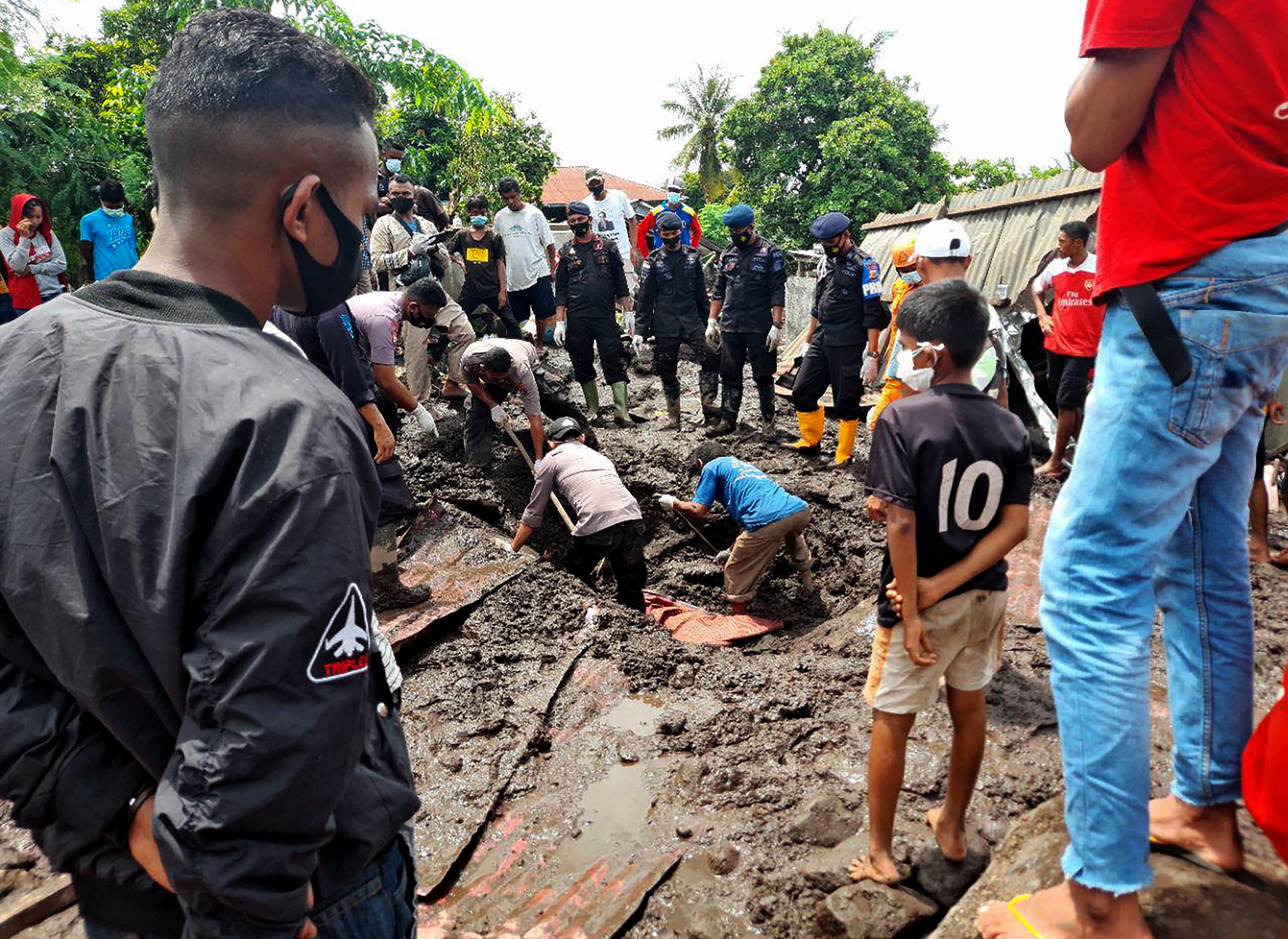 Residents watching as rescuers extract mud-covered bodies from the debris in Lamanele village, East Flores, after torrential rains from Tropical Cyclone Seroja hit the region in years, turned small communities into wastelands of mud photo.
