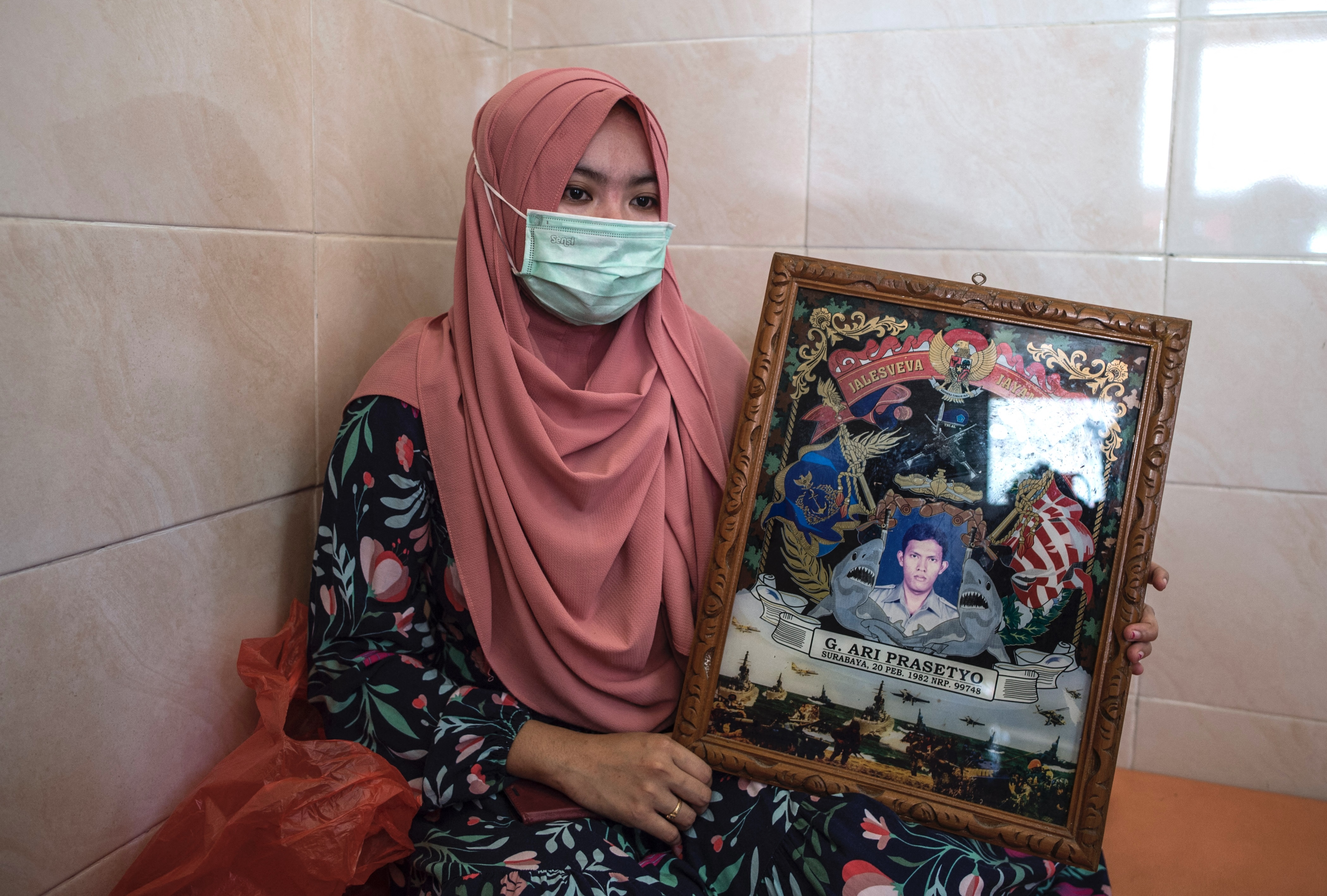 Berda Asmara shows a photo of her sailor husband Mes Guntur Ari Prasetyo at their home in Surabaya.