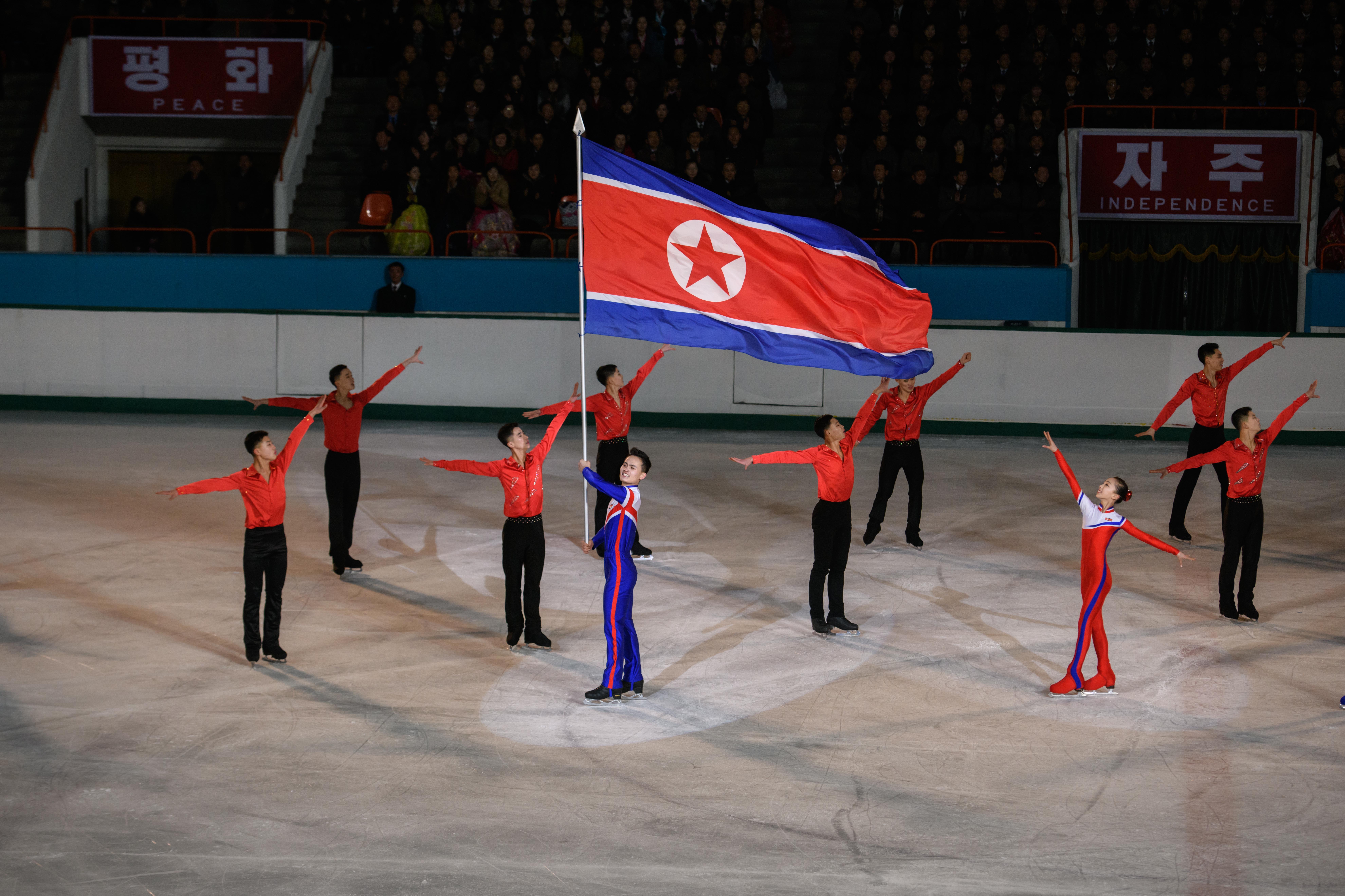 Olympic ice skater Kim Ju Sik (centre L) of North Korea holds a national flag during the '26th Paektusan Prize Figure Skating Festival in Celebration of the Day of the Shining Star' as part of celebrations marking the birthday of late North Korean leader Kim Jong Il, in Pyongyang photo.
