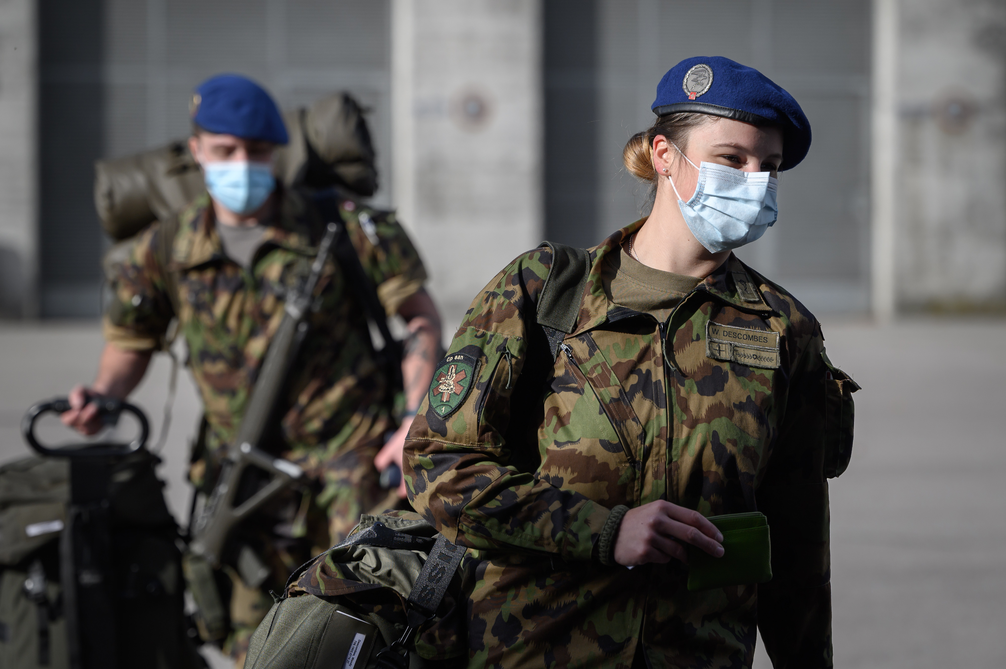 Swiss army reservists wearing protective face masks arrive at Moudon military photo.