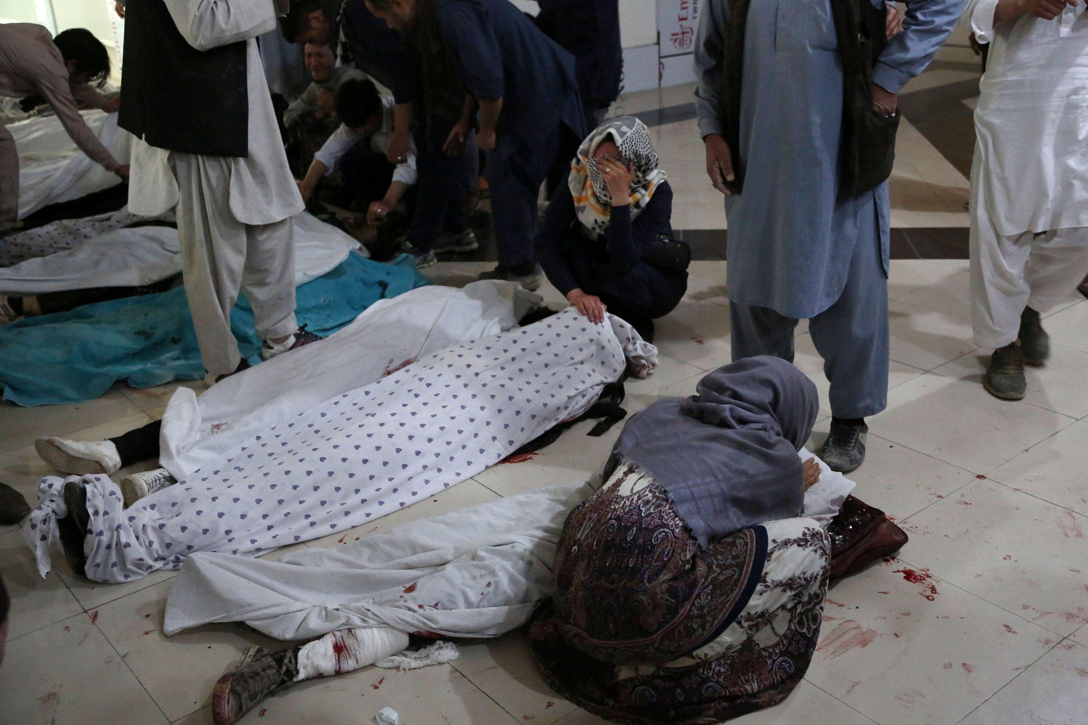 Family members and relatives mourn inside a hospital while sitting next to the bodies of victims who died in a blast outside a school in the west Kabul district of Dasht-e-Barchi, that killed at least 25 people and wounded scores more including students, officials said.