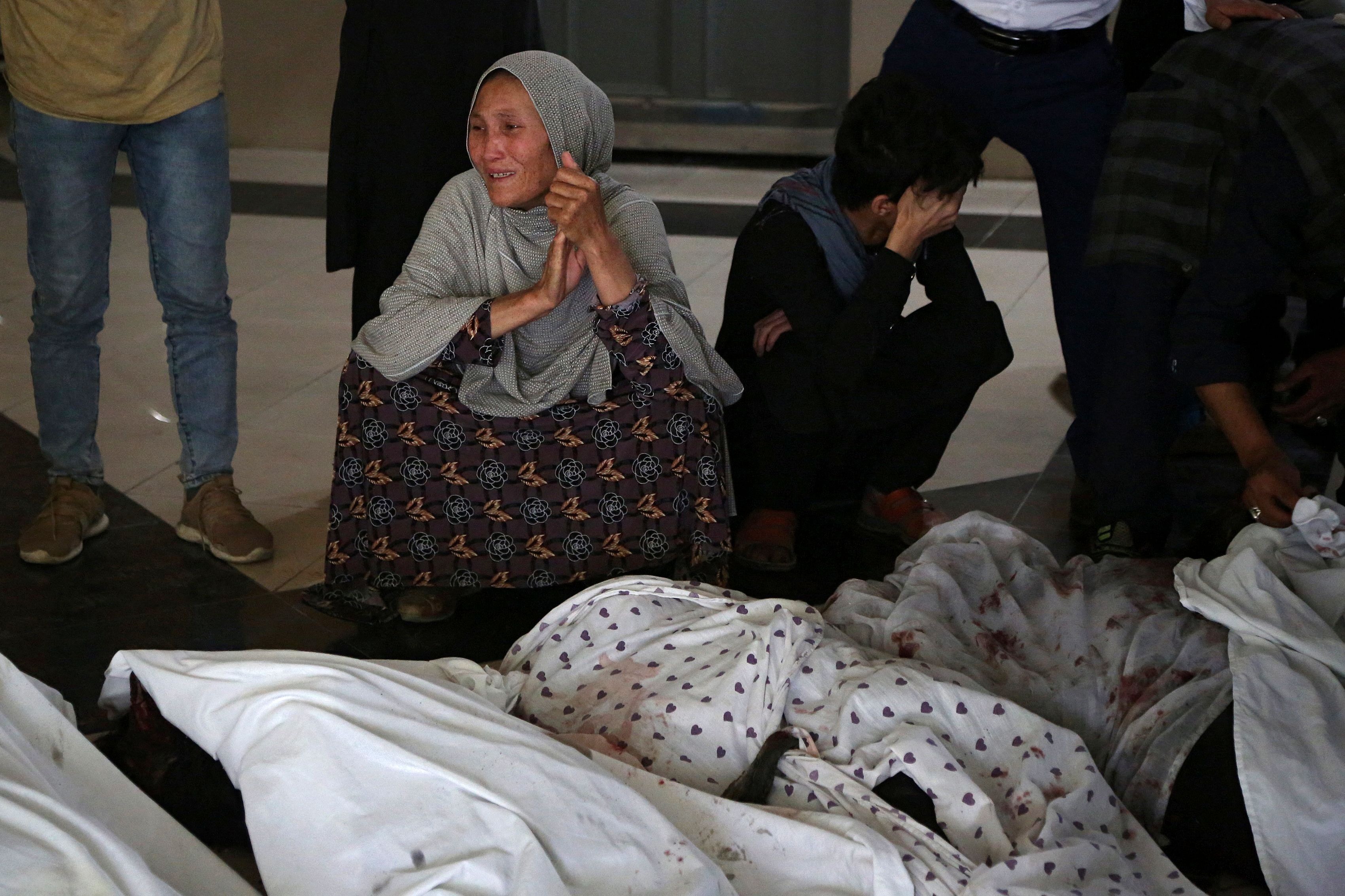 Family members and relatives mourn inside a hospital while sitting next to the bodies of victims who died in a blast outside a school in the west Kabul district of Dasht-e-Barchi.