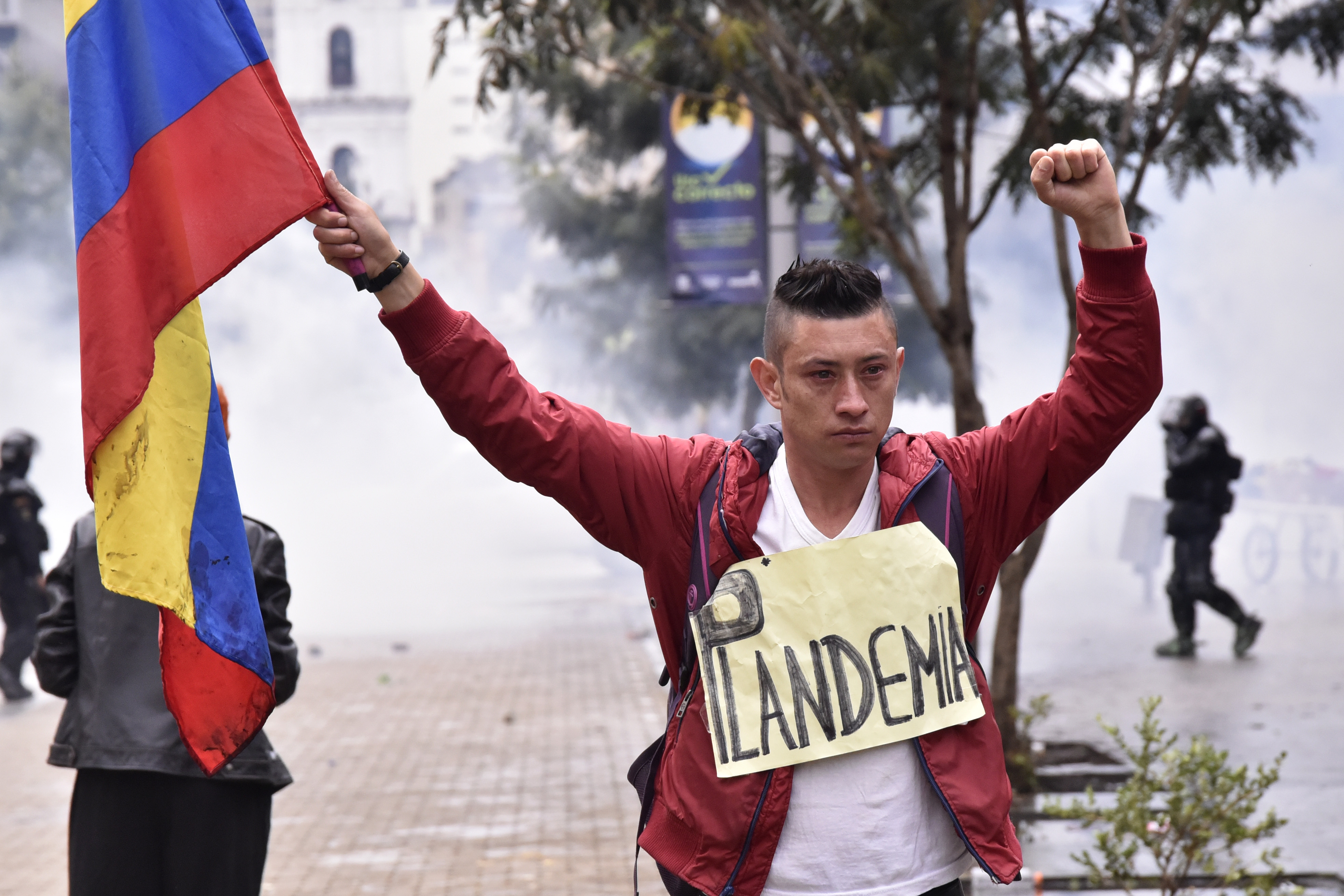 A protester holds a Colombian flag and a sign that reads "Plandemic" during the national strike against the tax reform proposed by Duque's administration in Bogota, Colombia. Unions joined to call to a national strike and demonstrations in major cities, urging participants to follow COVID-19 protocols. They seek to sink a tax reform which proposes elimination of VAT free goods.