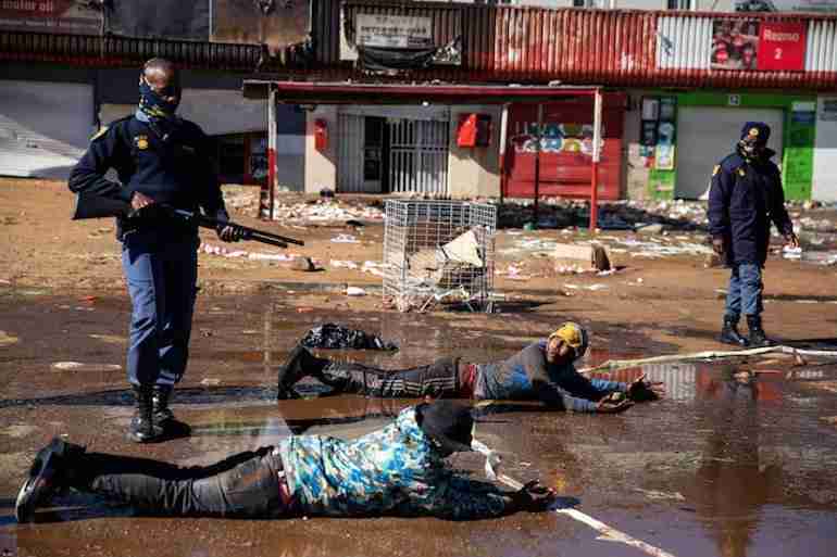South African police make suspected looters lie down and roll in muddy water.