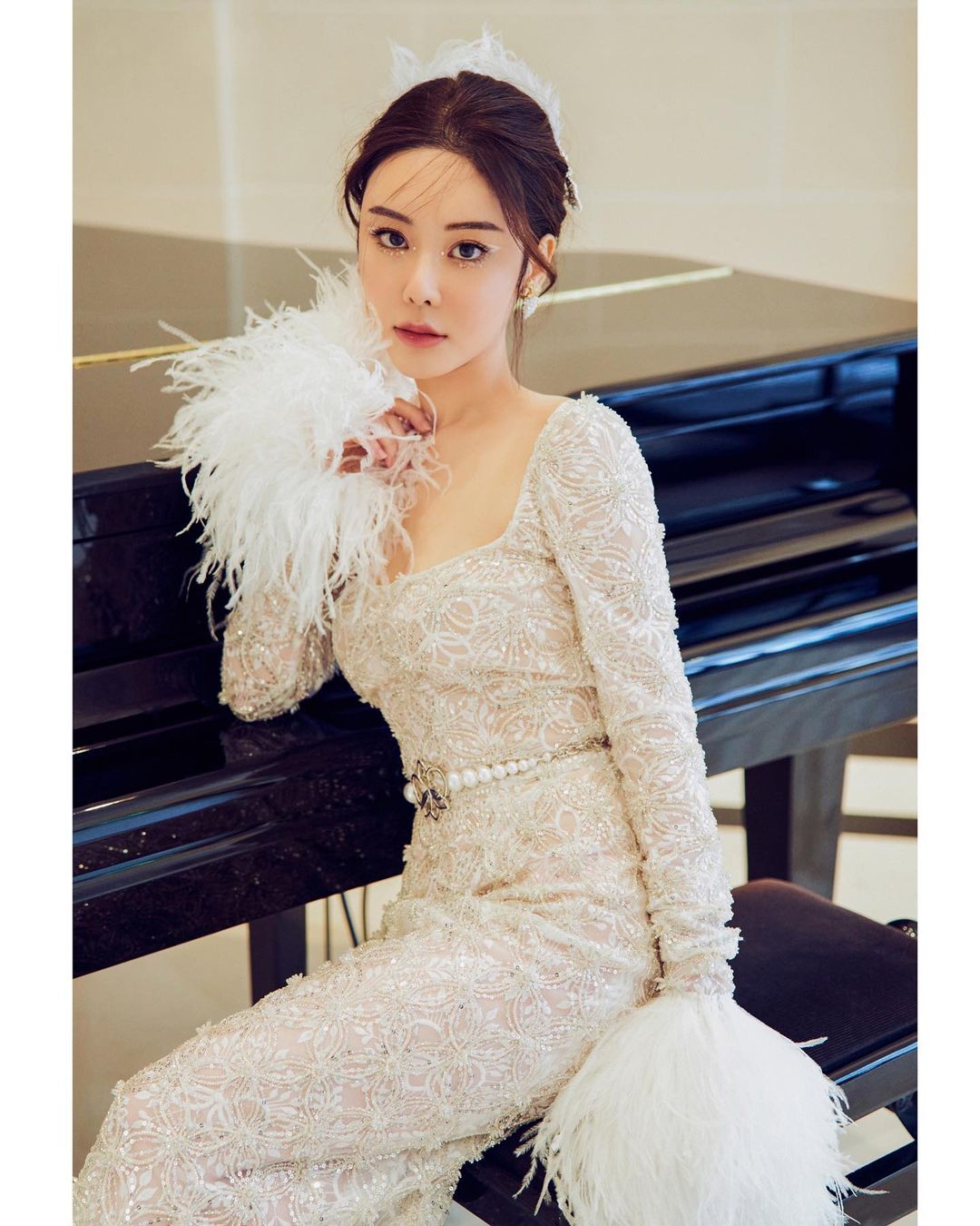 Abby Choi, a Hong Kong influencer sitting next to a piano and dressed in gown