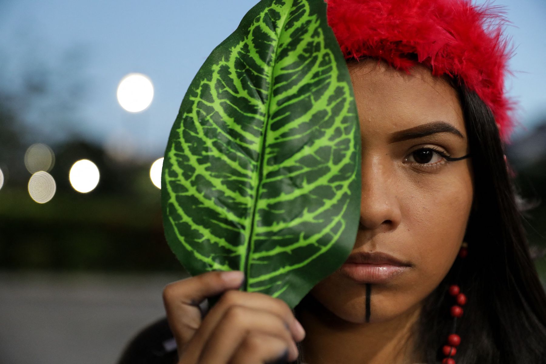 An Indigenous model using a leaf to pose in a picture to show of their unique fashion design