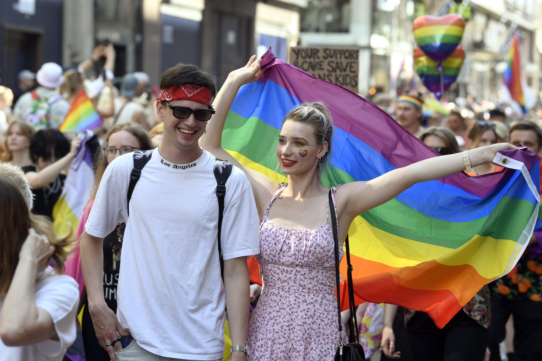 people holding rainbow flag at a pride parade