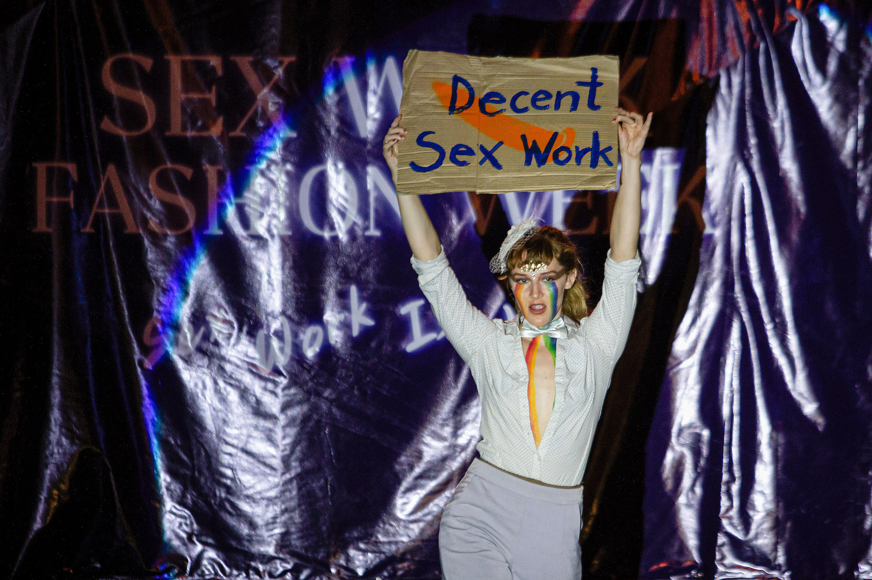 An activist holds a placard that says "Decent Sex Work" during a Sex Work Fashion Week on International Labor Day at the Tha Phae Gate