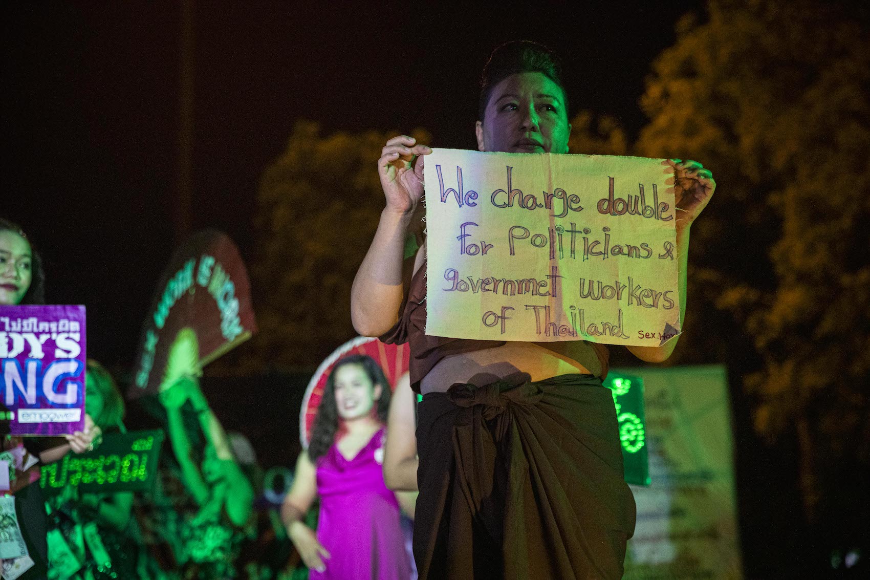 An activist holds a placard that says "We charge double For politicians & government workers of Thailand" during a Sex Work Fashion Week