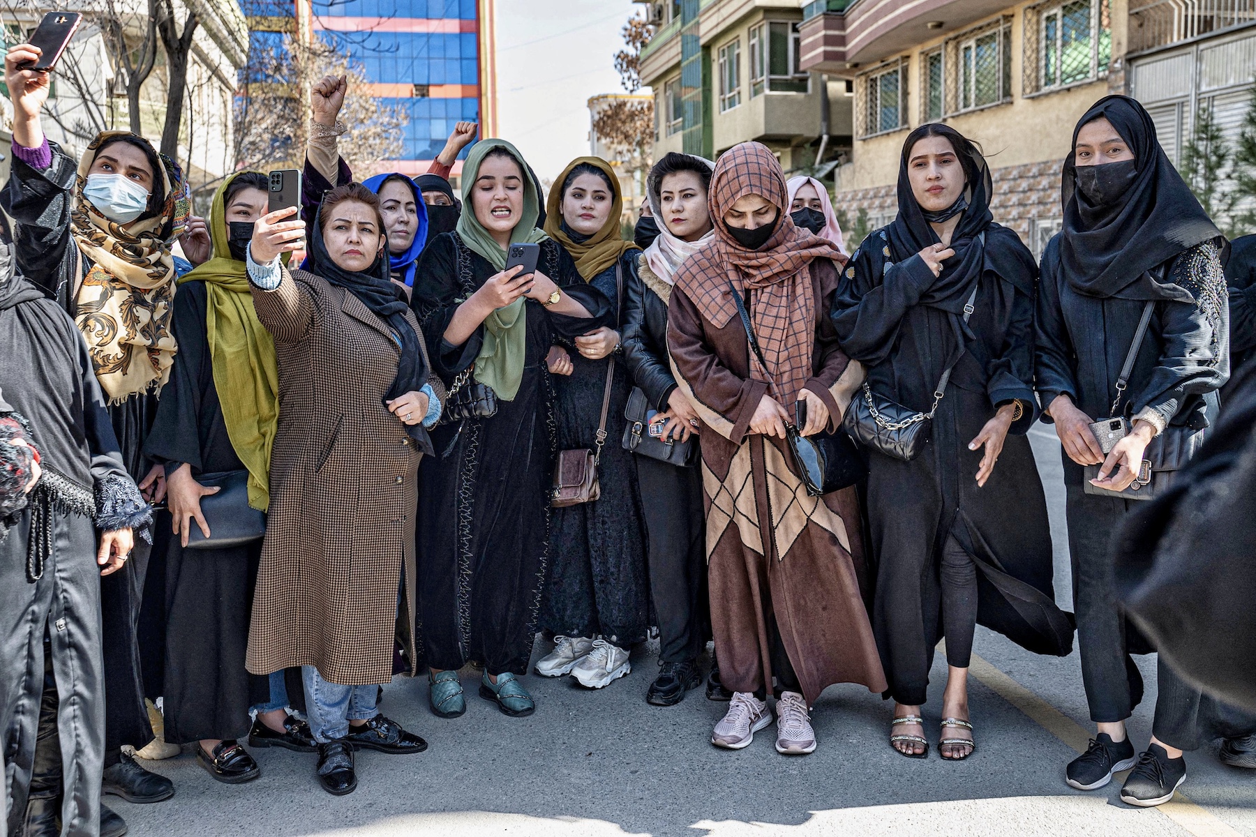 Women demonstrate on International Women's Day in Kabul, the capital of Afghanistan, while wearing headresses. Some of them seem to be appear to be snapping pictures by holding their phones up.