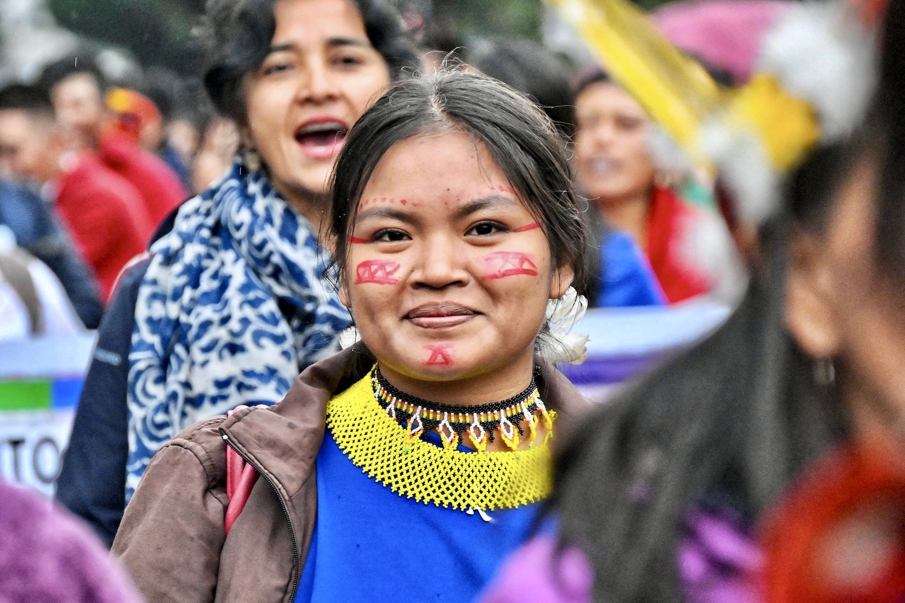Portrait of a smiling woman sporting face paint that resembles Indigenous markings. 