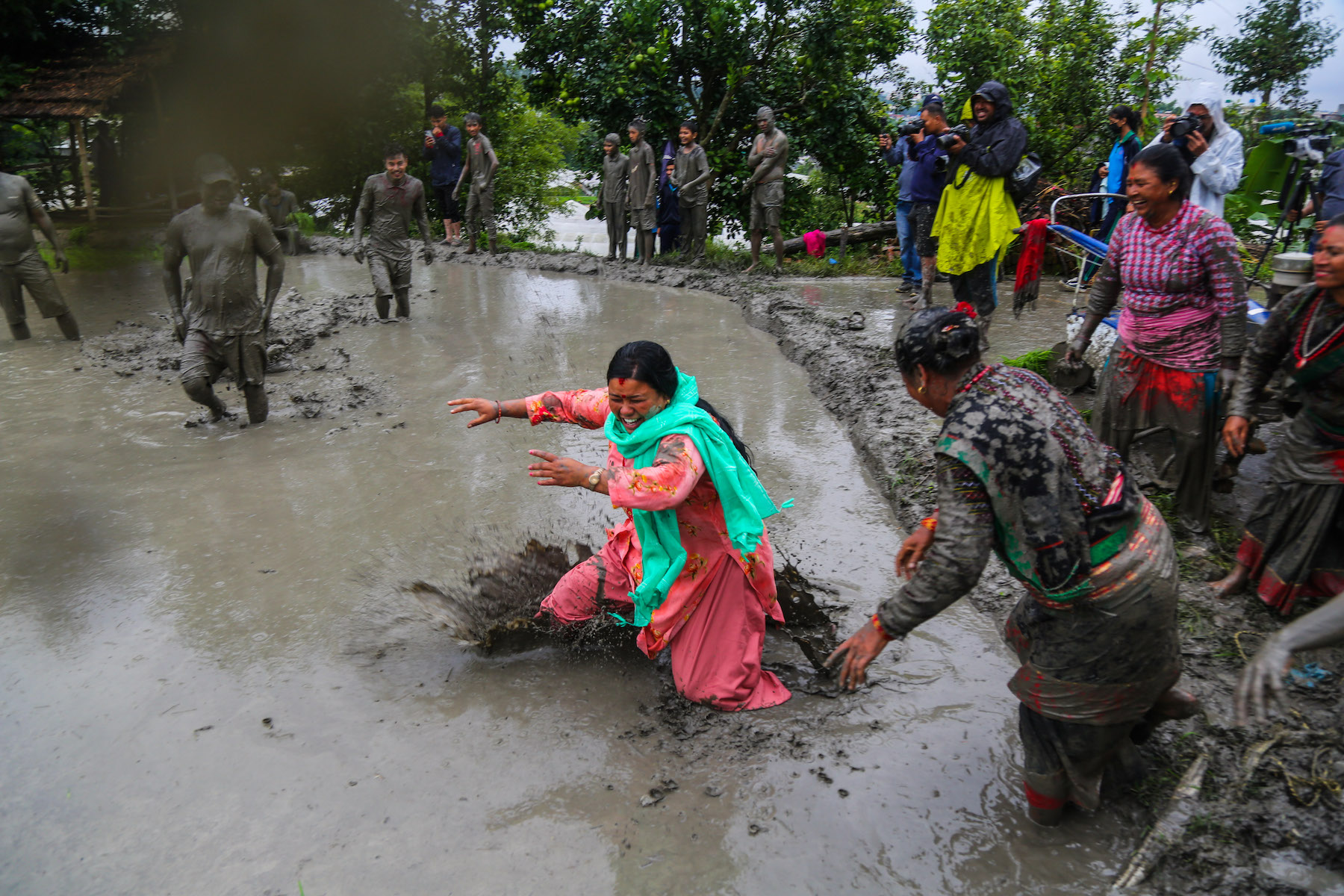 A woman enters a paddy field filled with mud.