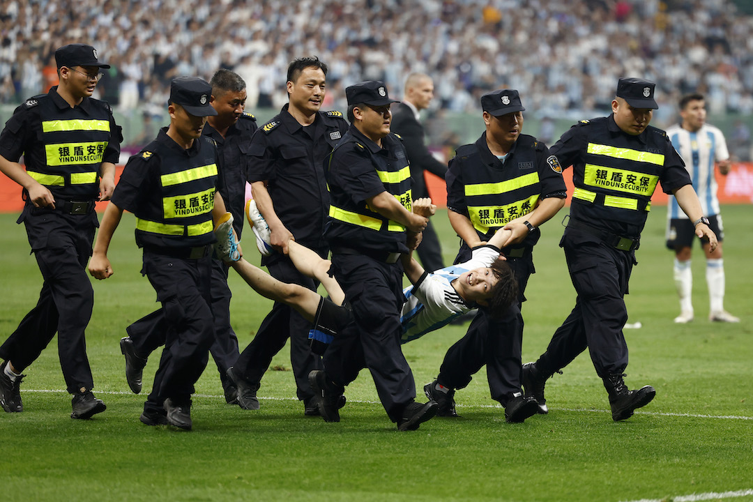 Chinese fan who invaded the pitch to hug Messi is carried away by security guards.