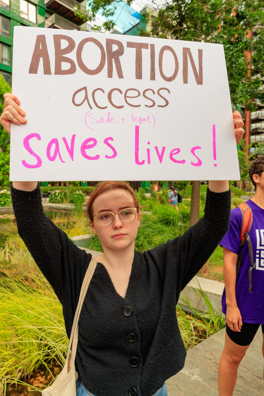 Woman holds sign that reads, "Abortion access saves lives!"