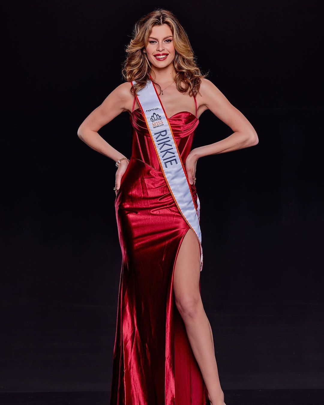 Rikkie Kolle, the first trans woman Miss Netherlands, is seen wearing a read dress and a sash bearing her name.