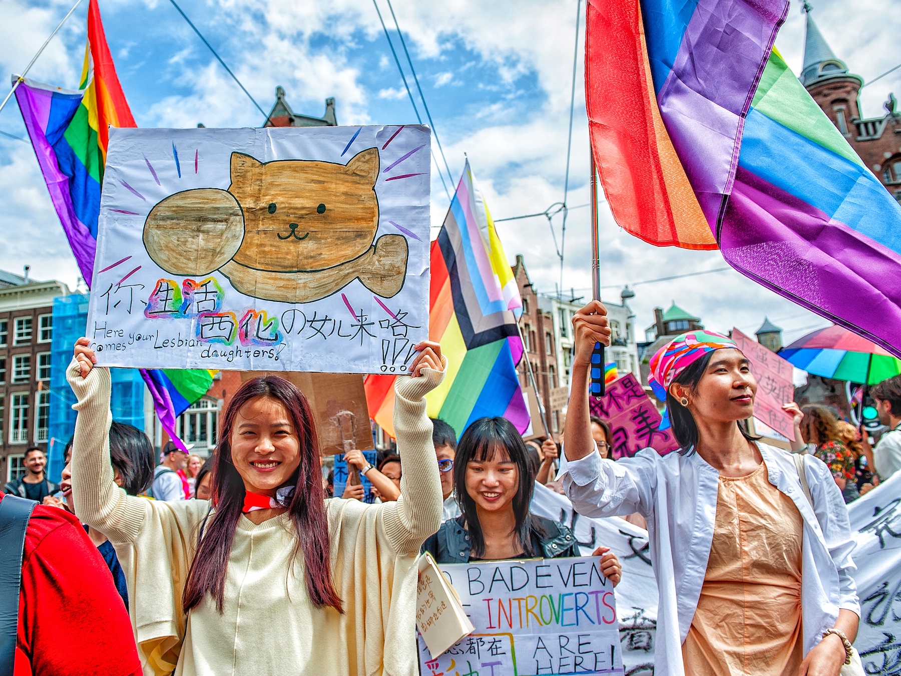 Asian people hold signs at Amsterdam's Pride parade