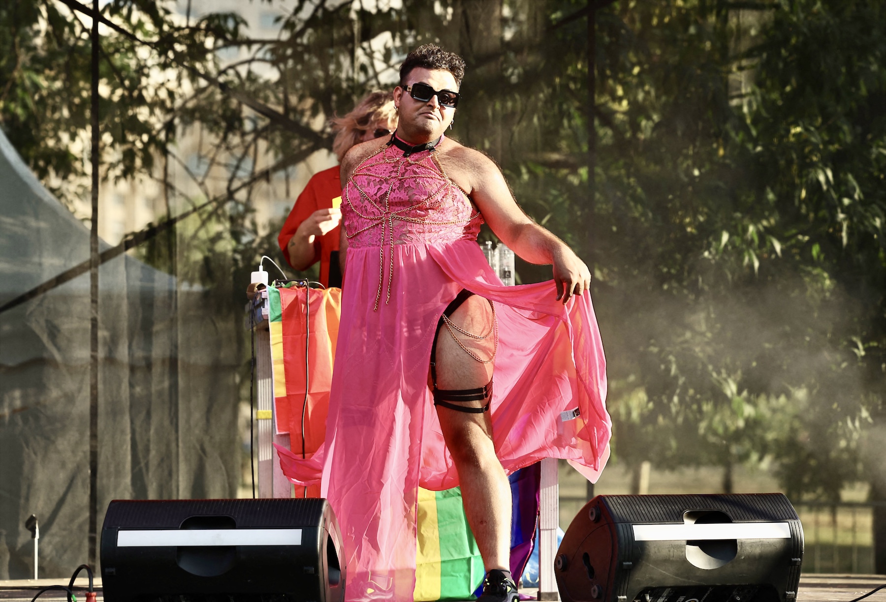 A man wears a pink dress and appears to stand on a stage during Romania's Pride march