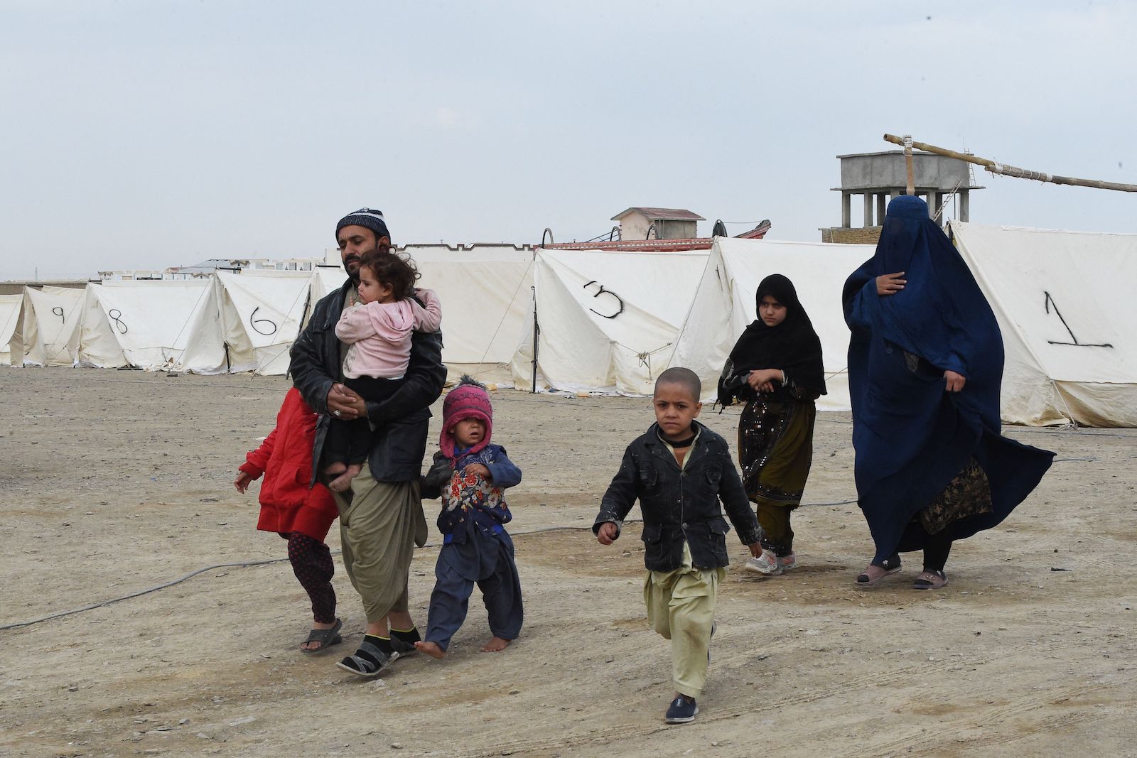 Afghan refugees walk near tents at a temporarily camp as they wait to cross the Pakistan Afghanistan border
