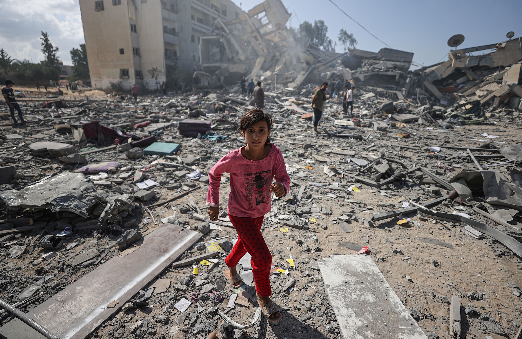 gaza girl walks amid the rubble of buildings