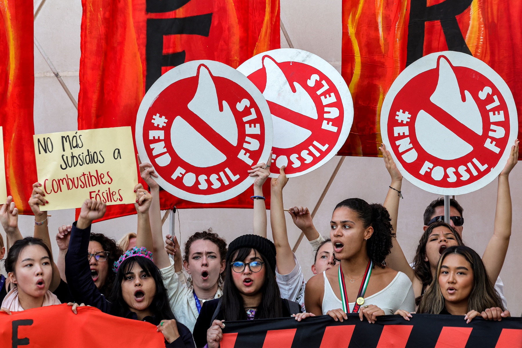 Climate activists raise placards during a protest against fossil fuels cop28 uae