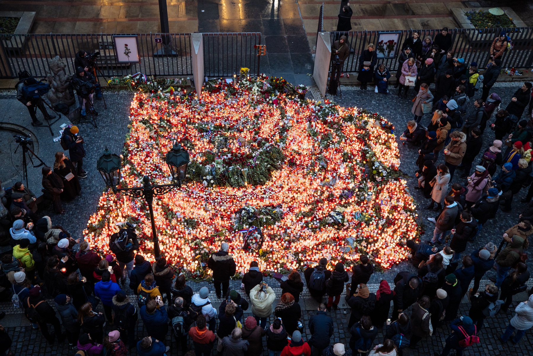 people lay flowers and light candles charles university prague