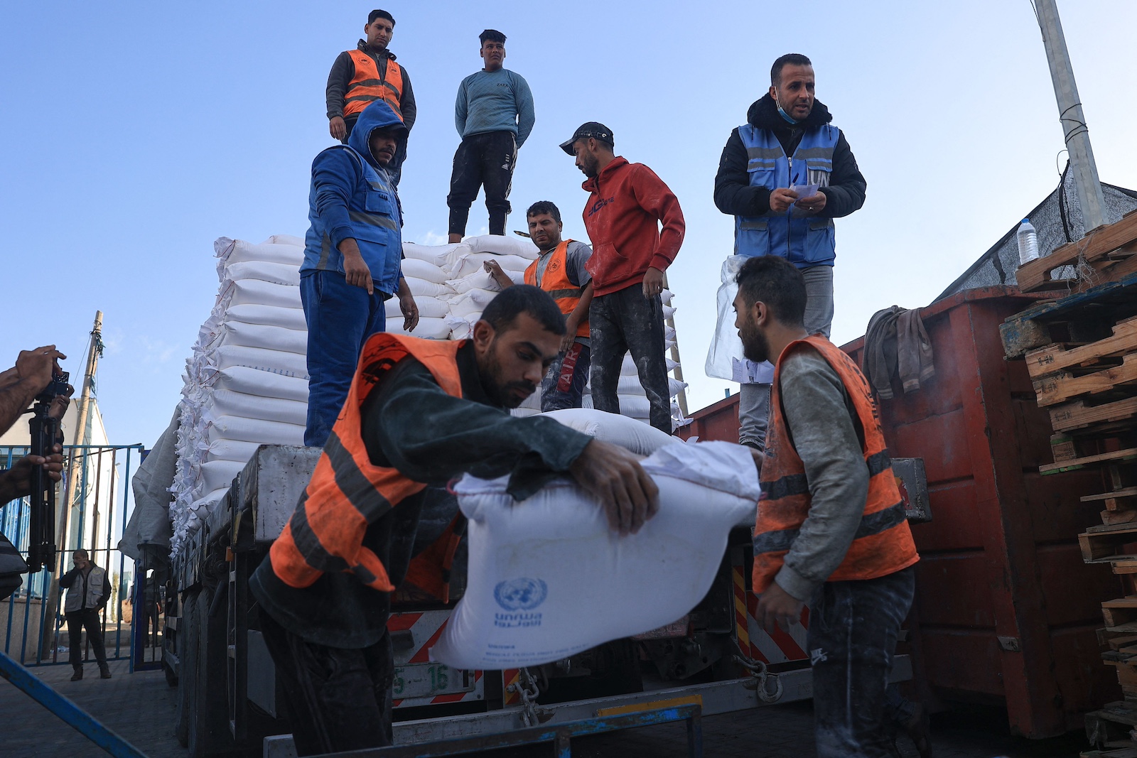 Palestinians receive bags of flour at the United Nations Relief UNRWA